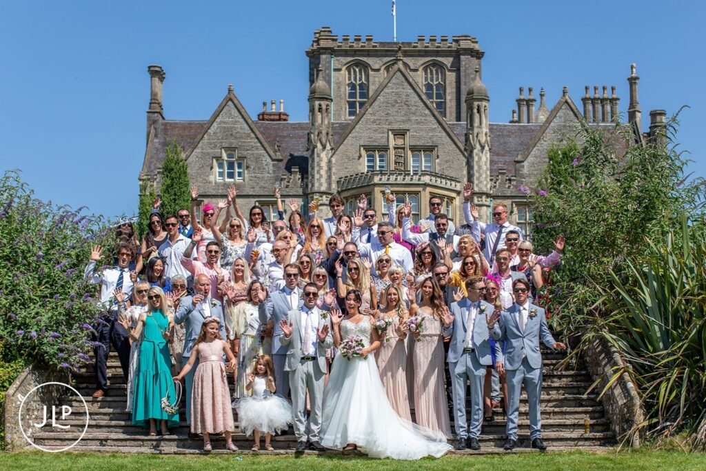 A large-scale photograph of all the wedding guests gathered on the stone steps of the manor house, a staple for Tortworth Court wedding photography.