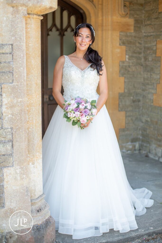 Bride Mel in her Alice Rose Bridal gown standing by the historic stone arches, documented by a Tortworth Court wedding photographer.