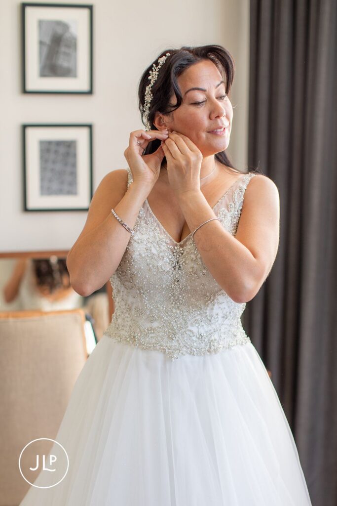 Bride Mel putting on earrings at Tortworth Court, captured by a Tortworth Court wedding photographer.