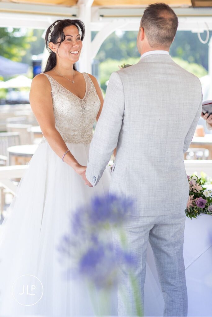 Mel and Ben holding hands during their ceremony, shot by an outdoor wedding photographer UK.