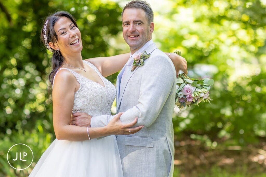 Laughing bride and groom embracing during their Gloucestershire wedding photographer portrait session.