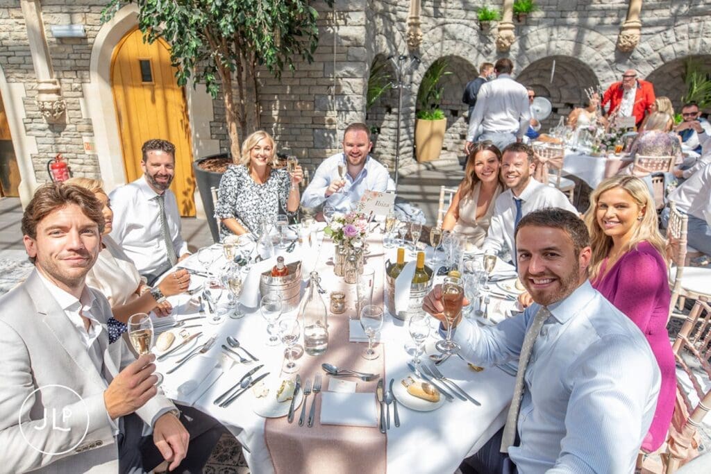 Smiling wedding guests seated at tables during a natural wedding photography Gloucestershire reception.