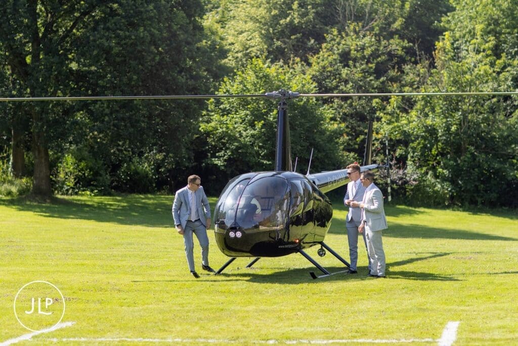 Groom arriving by helicopter for his luxury Gloucestershire wedding venue celebration.