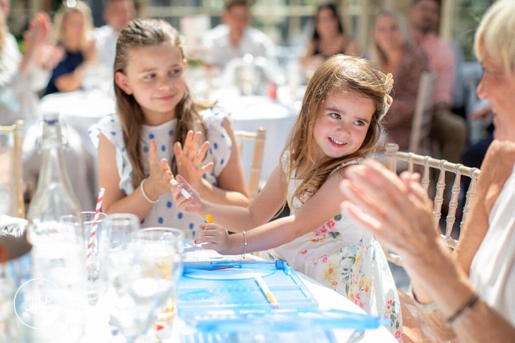 Happy children playing at the table, candidly shot by a professional wedding photographer UK.