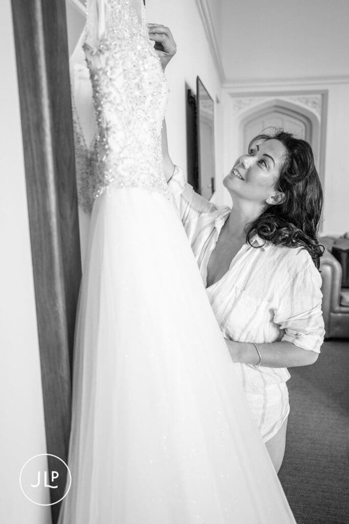 Smiling bride admiring her gown during natural wedding photography Gloucestershire morning.