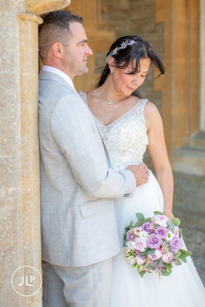 Romantic portrait of the bride and groom leaning against stone pillars at Tortworth Court.