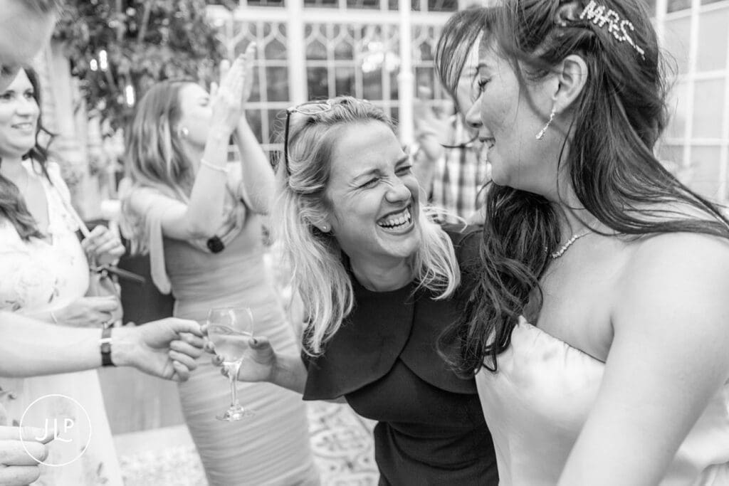 Laughing guests sharing a candid moment during a lively wedding photographer UK reception gallery.