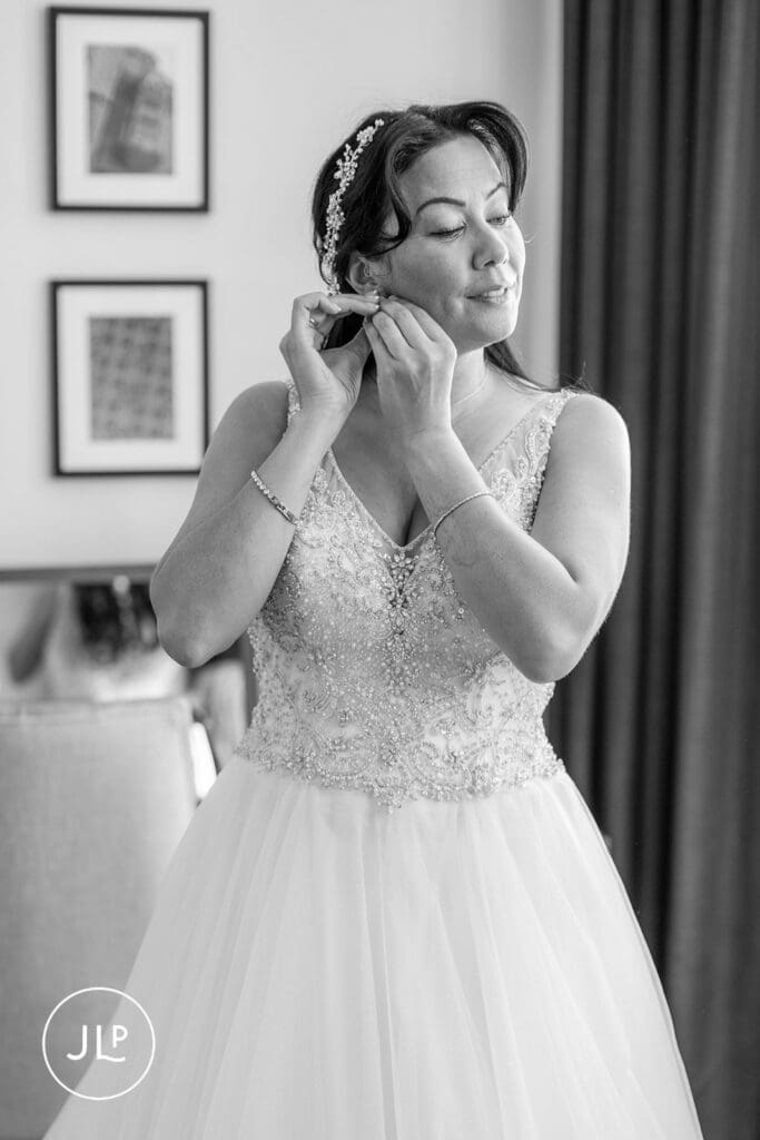 Bride putting on earrings, captured by a professional Gloucestershire wedding photographer.