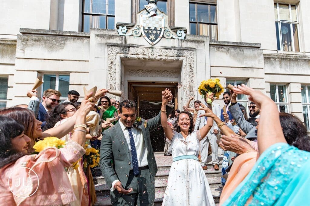 Bride and groom exit Wandsworth Town Hall wedding ceremony as guests throw confetti.