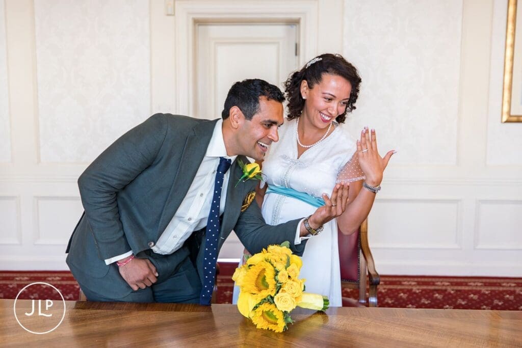Happy bride and groom showing their wedding rings at Wandsworth Town Hall registry office.