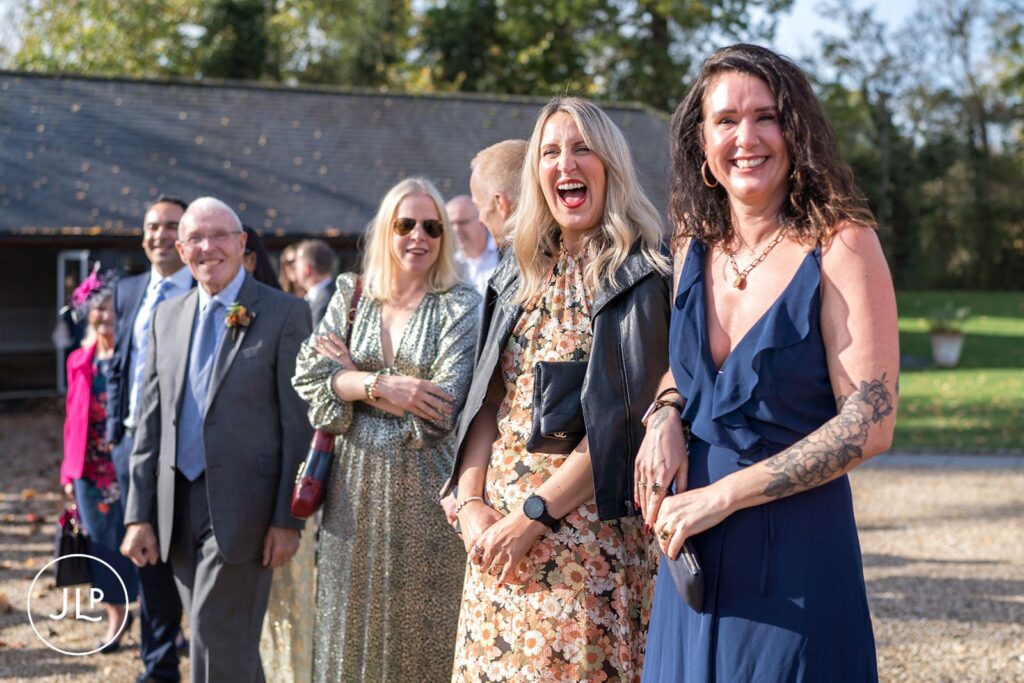Candid wedding photography capturing joyful guest moments during an outdoor wedding drinks reception.