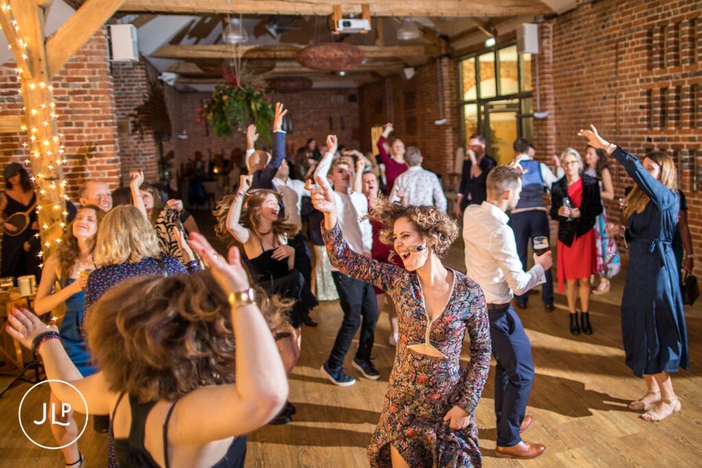 Guests dancing on a crowded dance floor during a fun evening reception, by a Wasing Park wedding photographer.