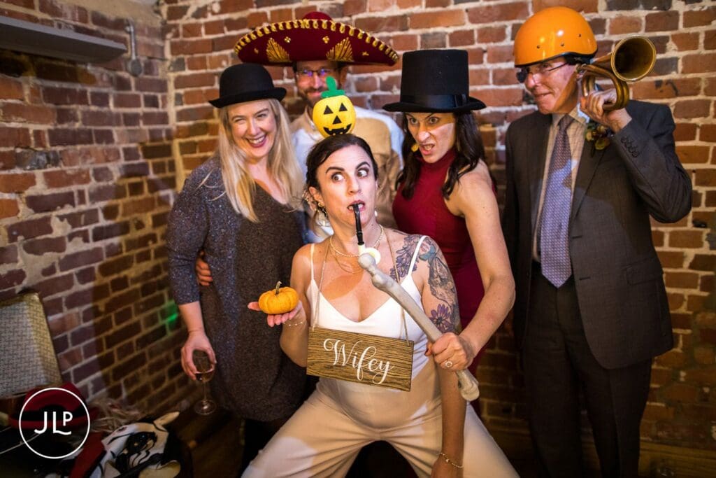 Bride wearing a wifey sign posing with guests in funny hats, showing fun wedding photography in Berkshire.