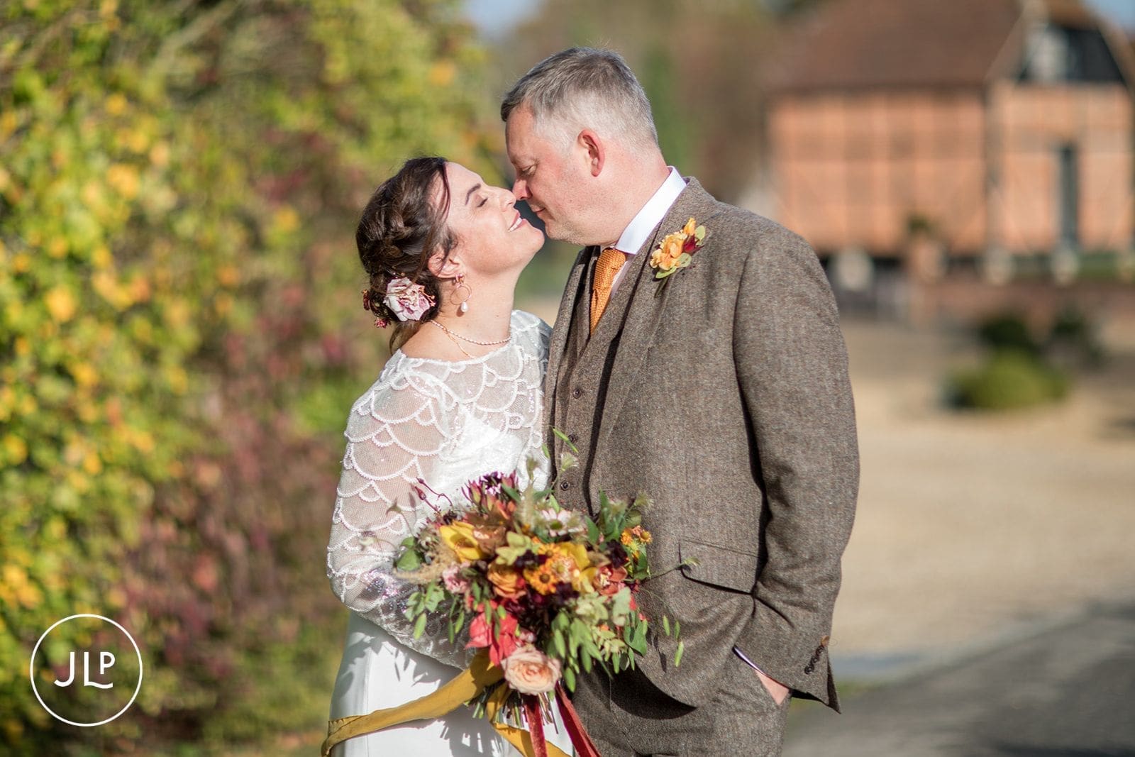 Romantic close-up of a bride and groom smiling together during their autumn countryside wedding.