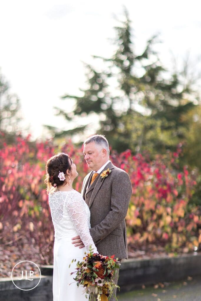 Natural wedding photography of a bride and groom surrounded by rich red autumn foliage in Berkshire.