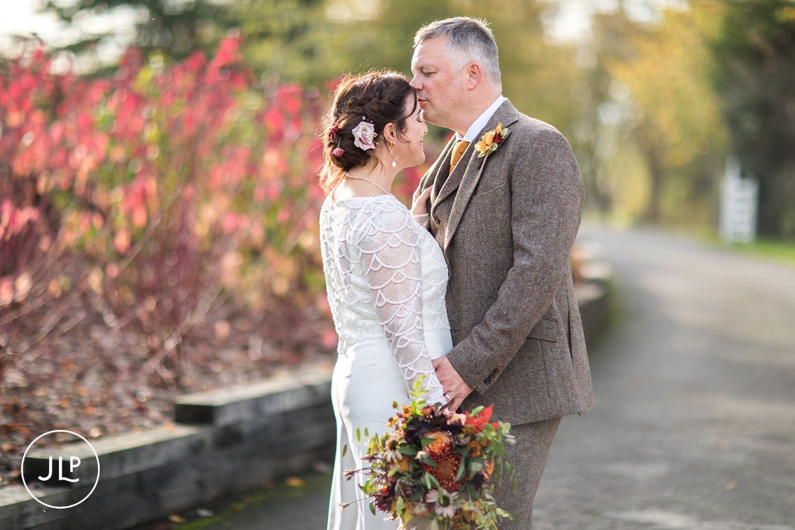 Groom kissing the bride's forehead during their autumn wedding celebration at a Berkshire countryside venue.