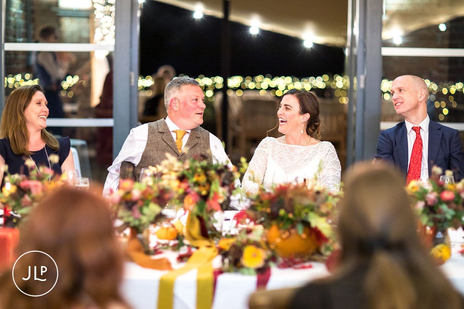 The bride and groom laughing together at the top table during the wedding speeches at Wasing Park.