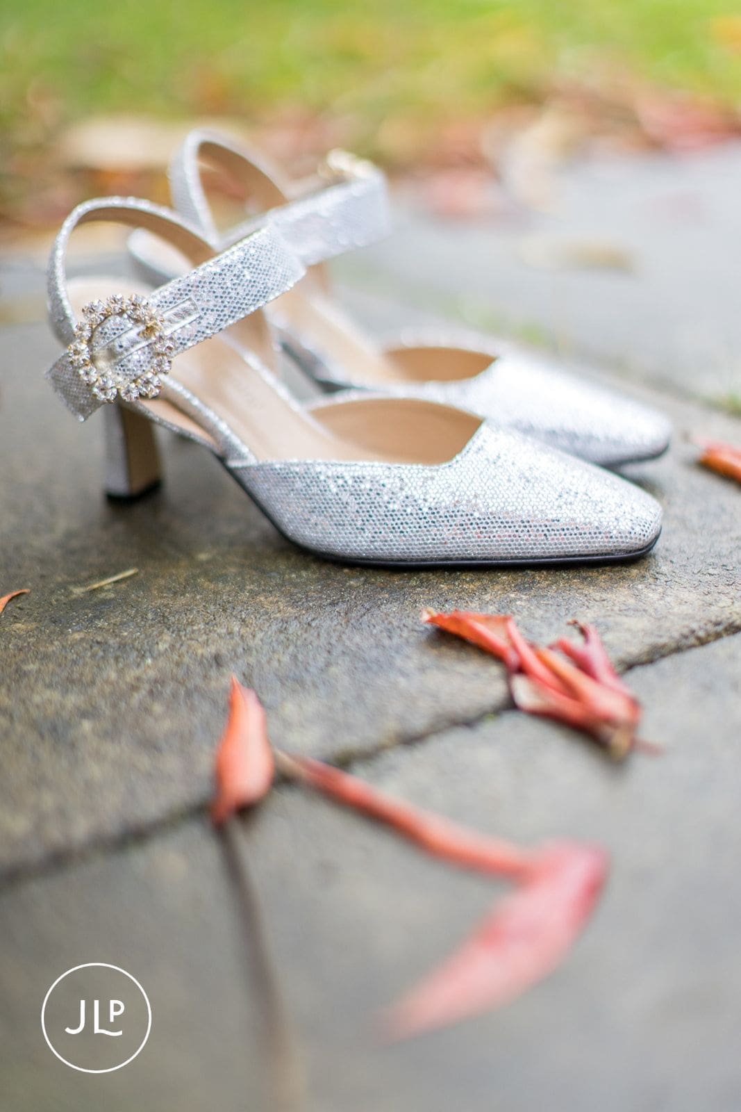 Close-up of sparkly silver bridal shoes on autumn leaves at a stylish Berkshire wedding.