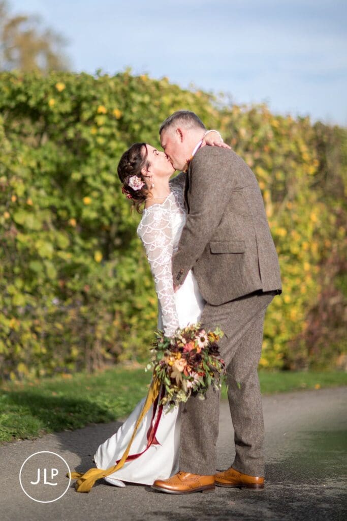 Fun wedding photography of the groom dipping and kissing the bride outdoors at Wasing Park Berkshire.