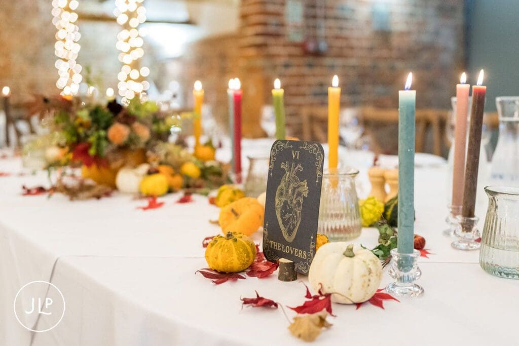 The Lovers tarot card table setting with colorful candles and mini pumpkins for autumn wedding inspiration.