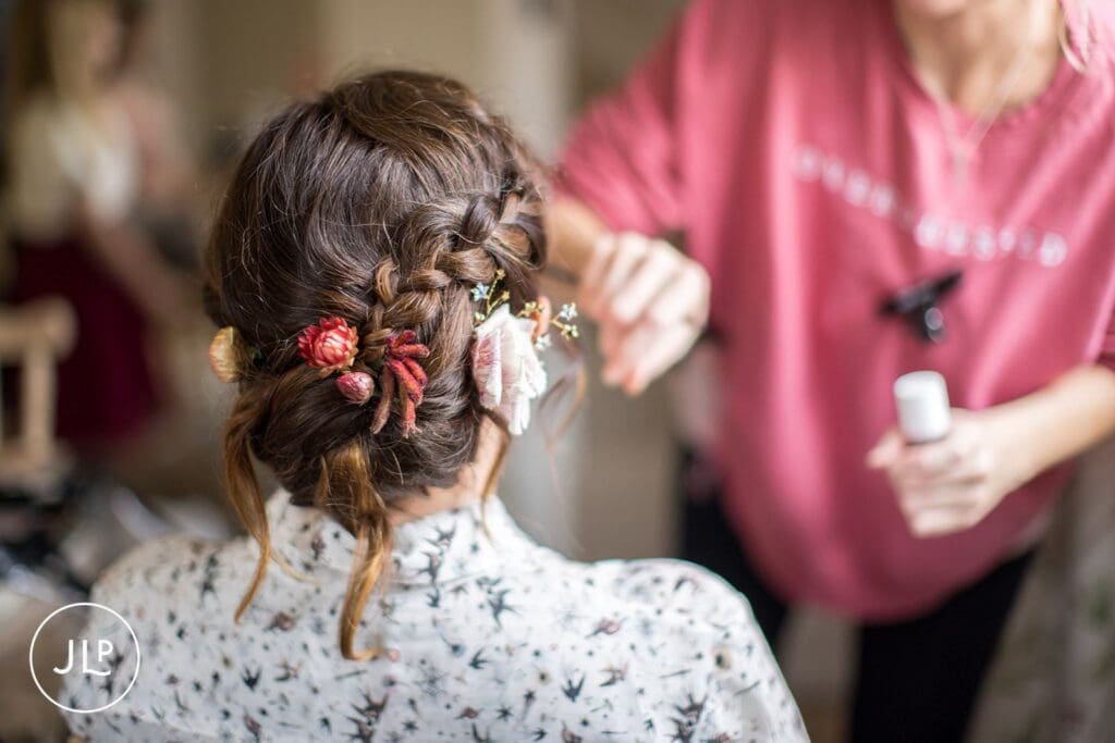 Candid wedding photography of a bride getting her hair styled during morning preparations.