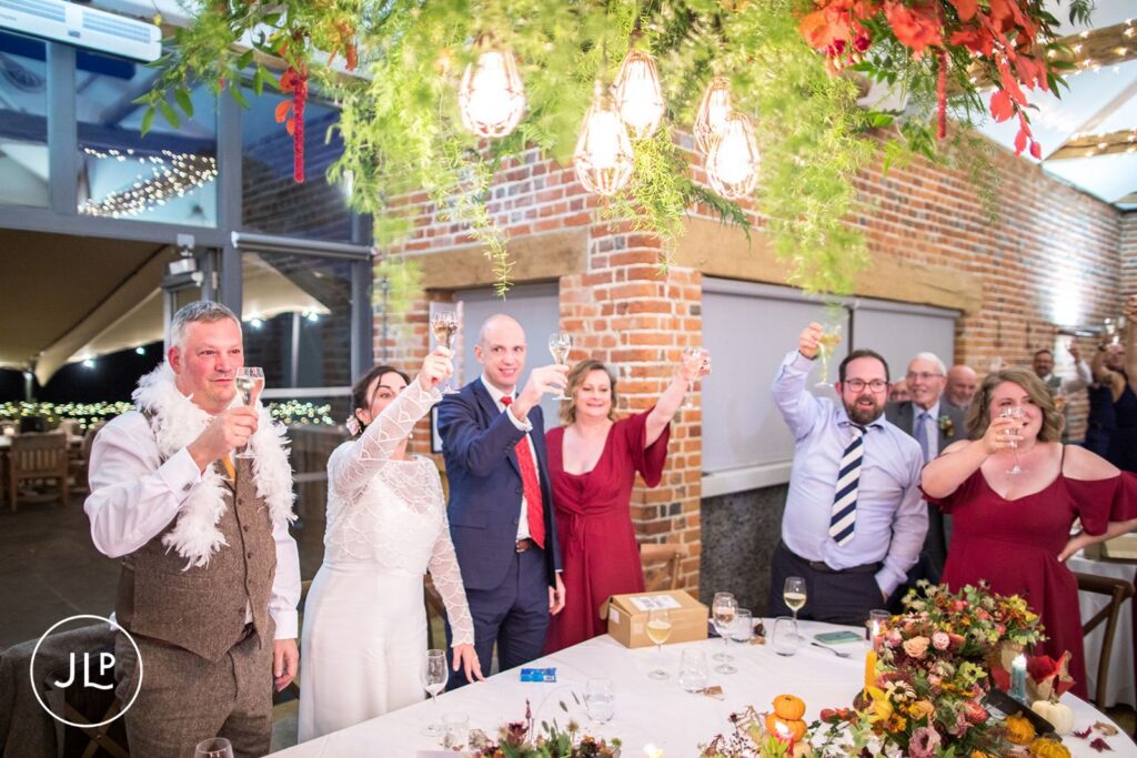 Newlyweds and guests raising a toast beneath hanging foliage, captured by a Berkshire wedding photographer.