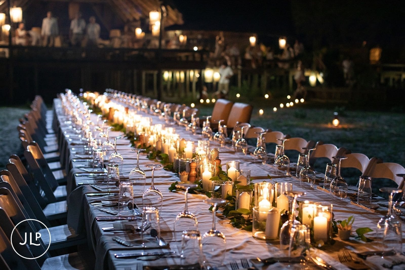 A beautifully styled outdoor wedding breakfast setup beside a lagoon under the African sky.
