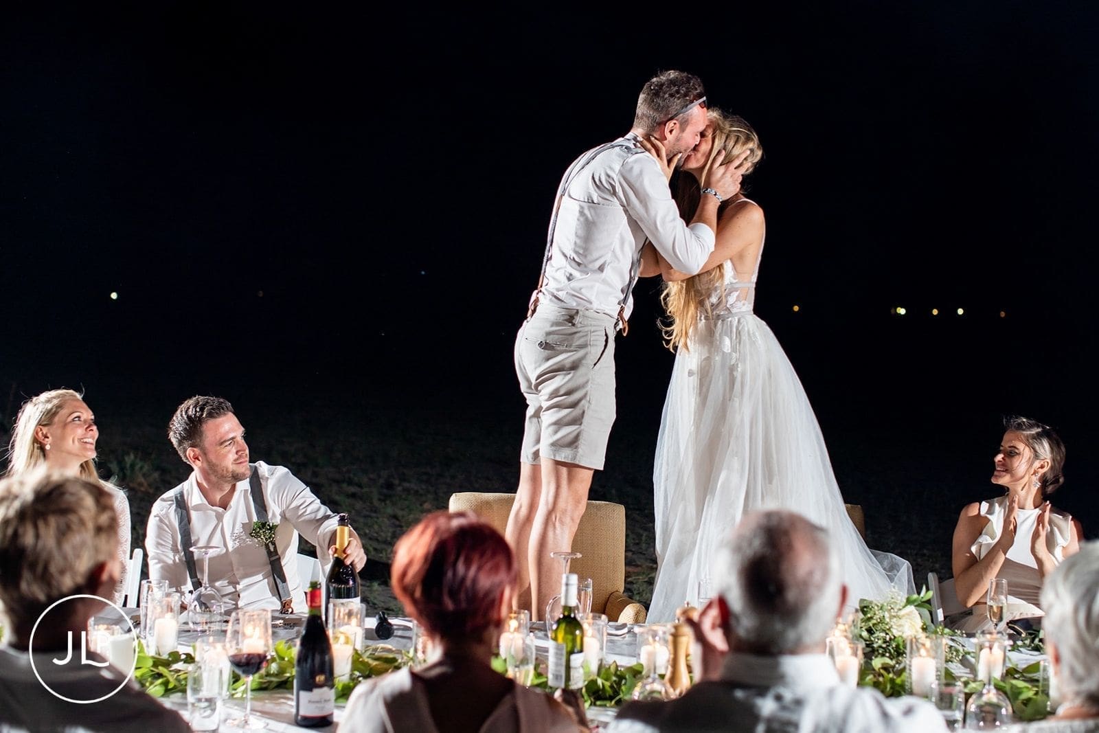 Groom stands on a chair to kiss the bride during a safari wedding Botswana reception.