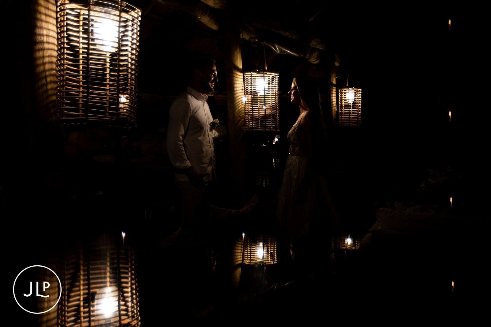 Bride and groom illuminated by lanterns during an intimate safari celebration at night.