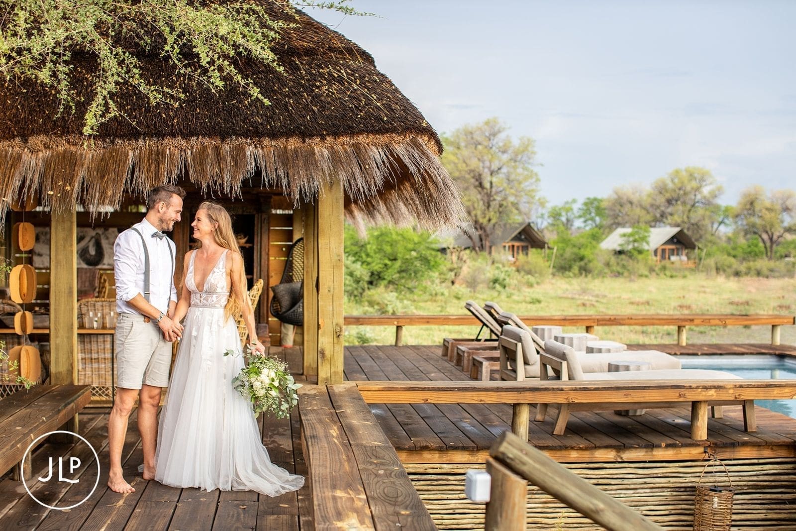Bride and groom smile at each other on a wooden deck at a luxury safari wedding Botswana.