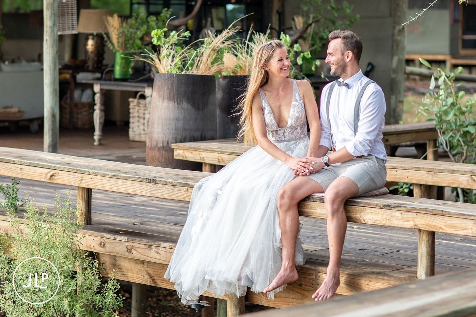 Relaxed portrait of a bride and groom sitting on a wooden bench for natural wedding photography Botswana.
