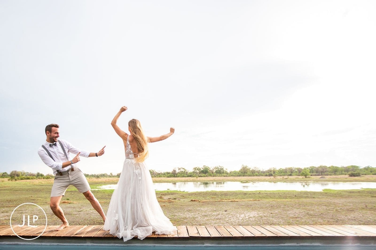Newlyweds dancing on a wooden boardwalk overlooking the breathtaking Okavango Delta.