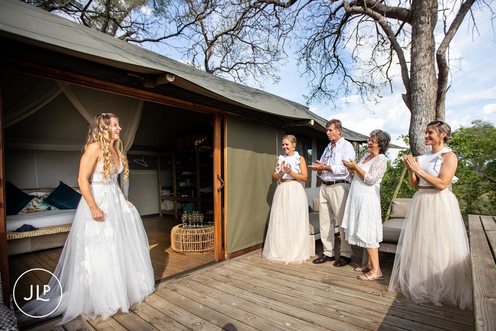 Bride reveals her dress to guests outside a luxury safari lodge tent in Botswana.
