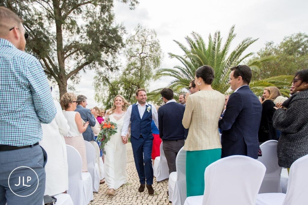 Newlyweds walking down the aisle at an outdoor Algarve vineyard wedding ceremony in Portugal.