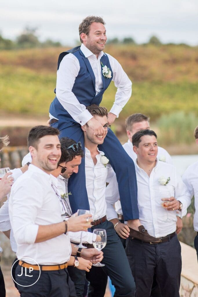 Groom carried by friends during a lively reception, shot by a Quinta dos Vales wedding photographer.