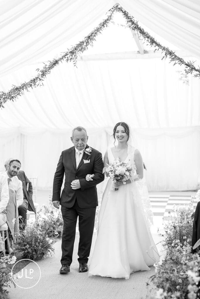 Elegant bride walking down the aisle with her father, captured by a Surrey wedding photographer.