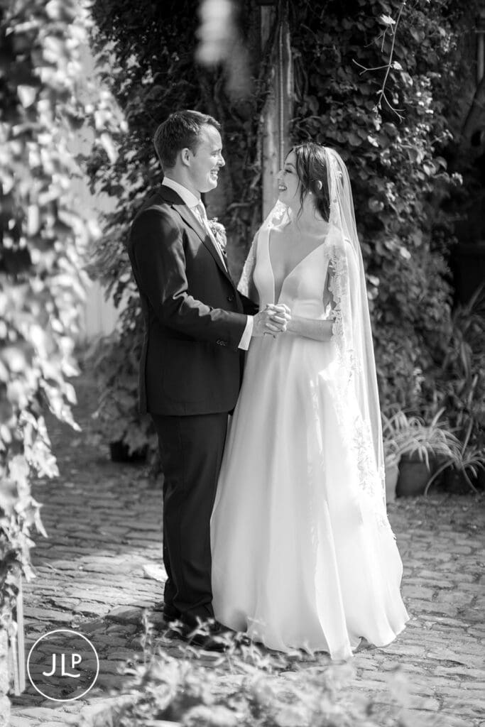 Natural wedding photography of a smiling bride and groom holding hands outside a Surrey wedding venue.