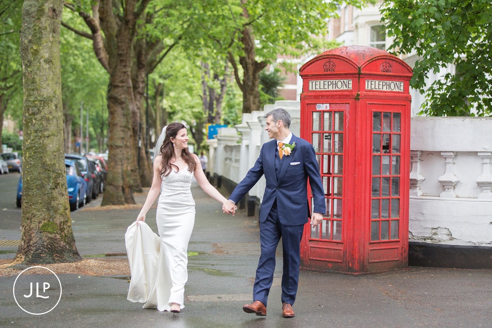 Natural London wedding photography of a couple walking past a classic red phone booth.