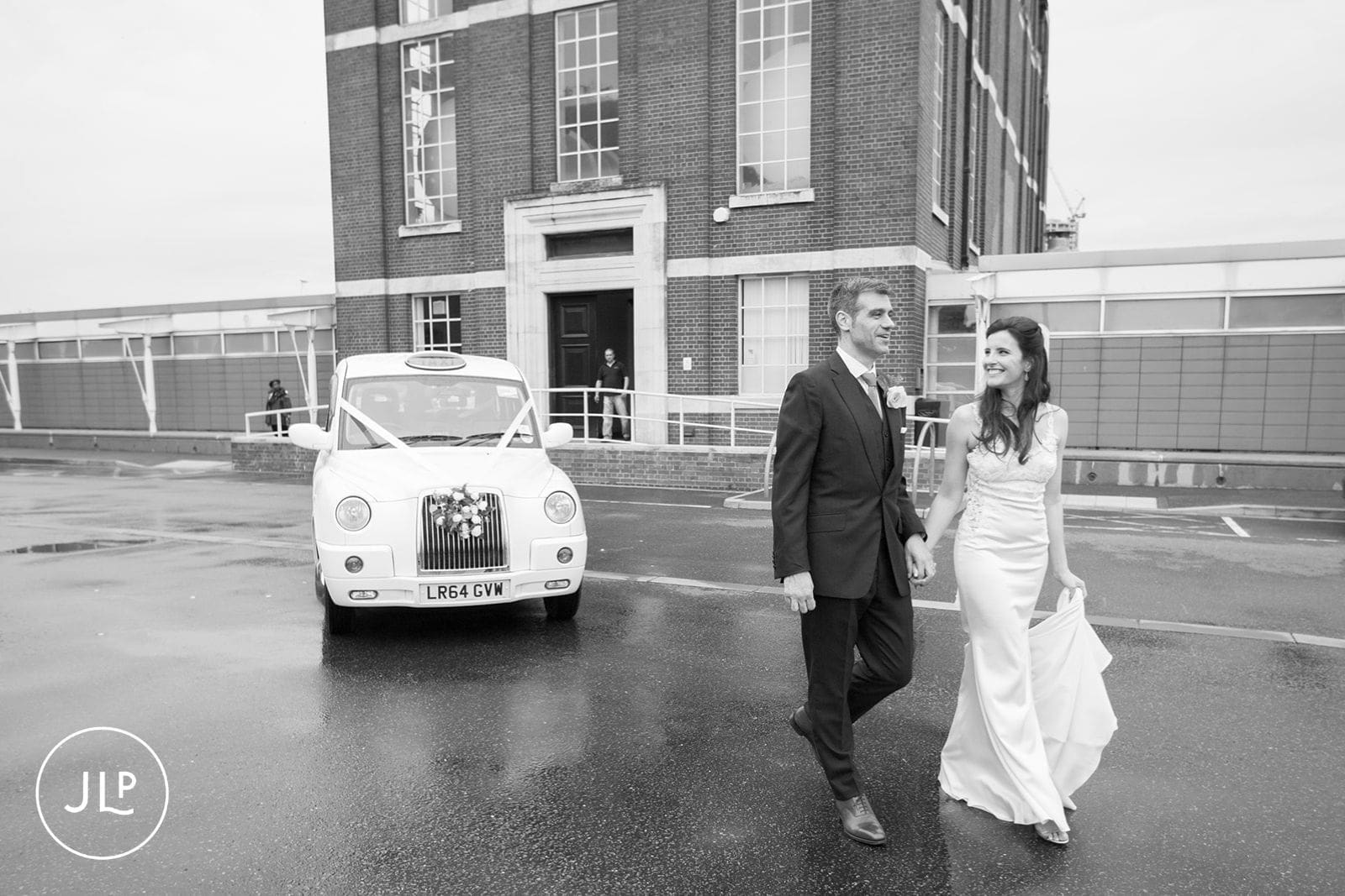 Bride and groom arriving in a classic white cab at an East London wedding venue.