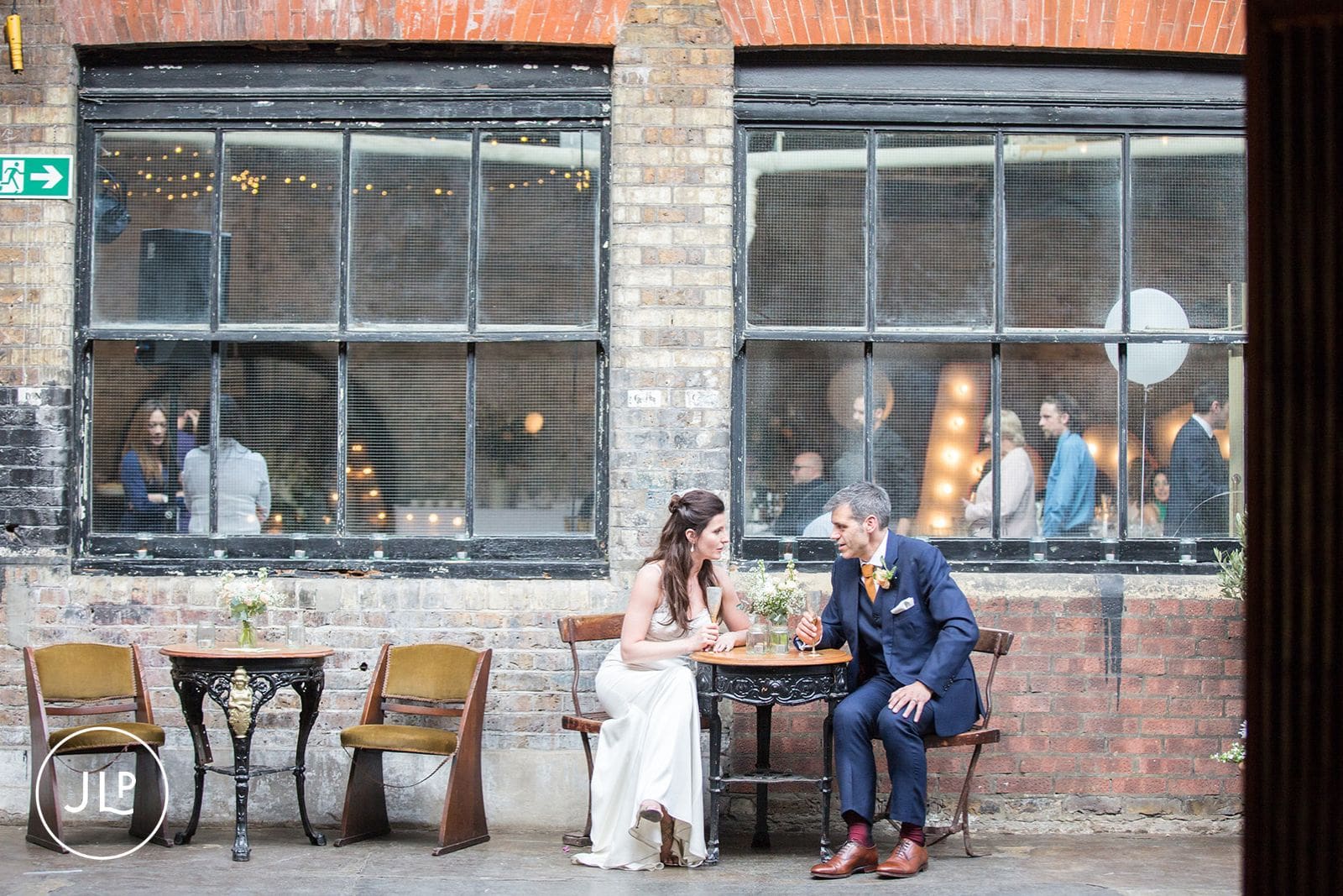 Bride and groom sitting at a table together in an intimate courtyard during their London wedding.