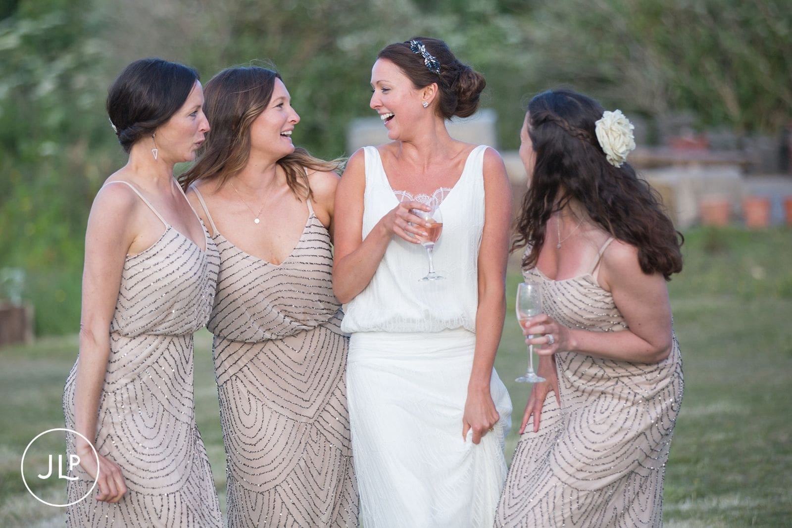 Bride in a Charlie Brear wedding dress drinking champagne with her bridesmaids outdoors in Alderney.