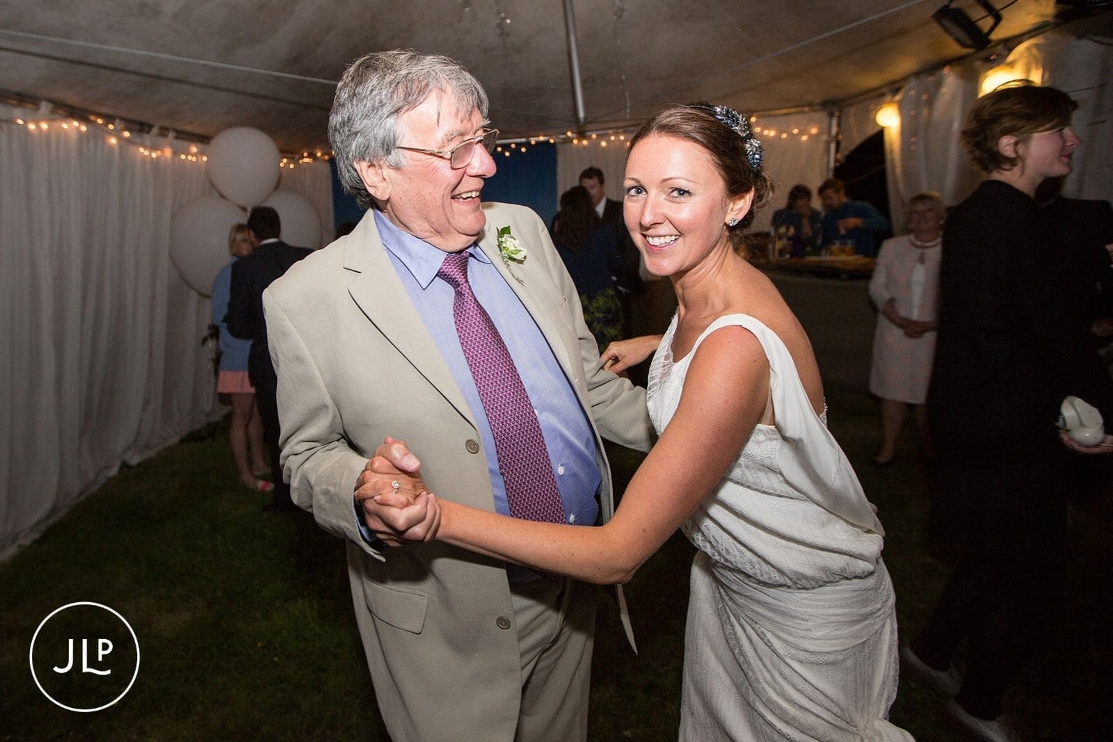 Bride laughing while dancing with an older guest during a relaxed marquee wedding reception in Alderney.