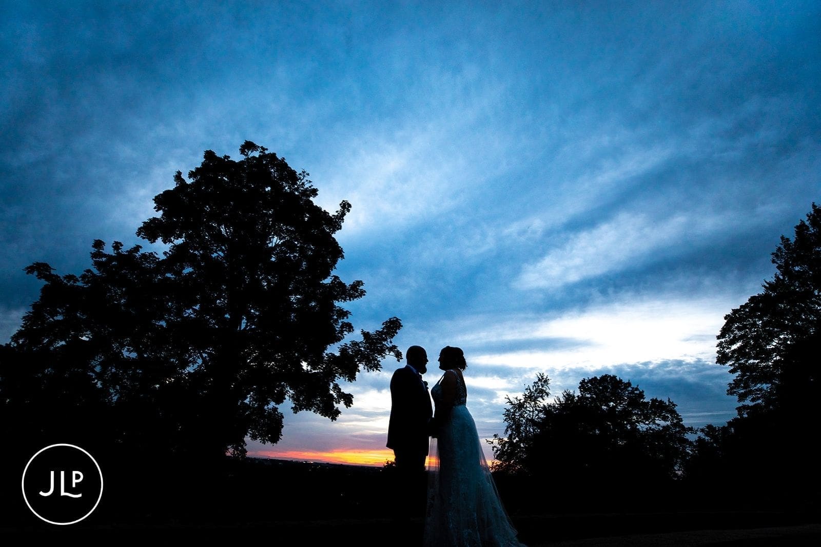Stunning sunset silhouette portrait of a married couple, highlighting creative wedding photography light.