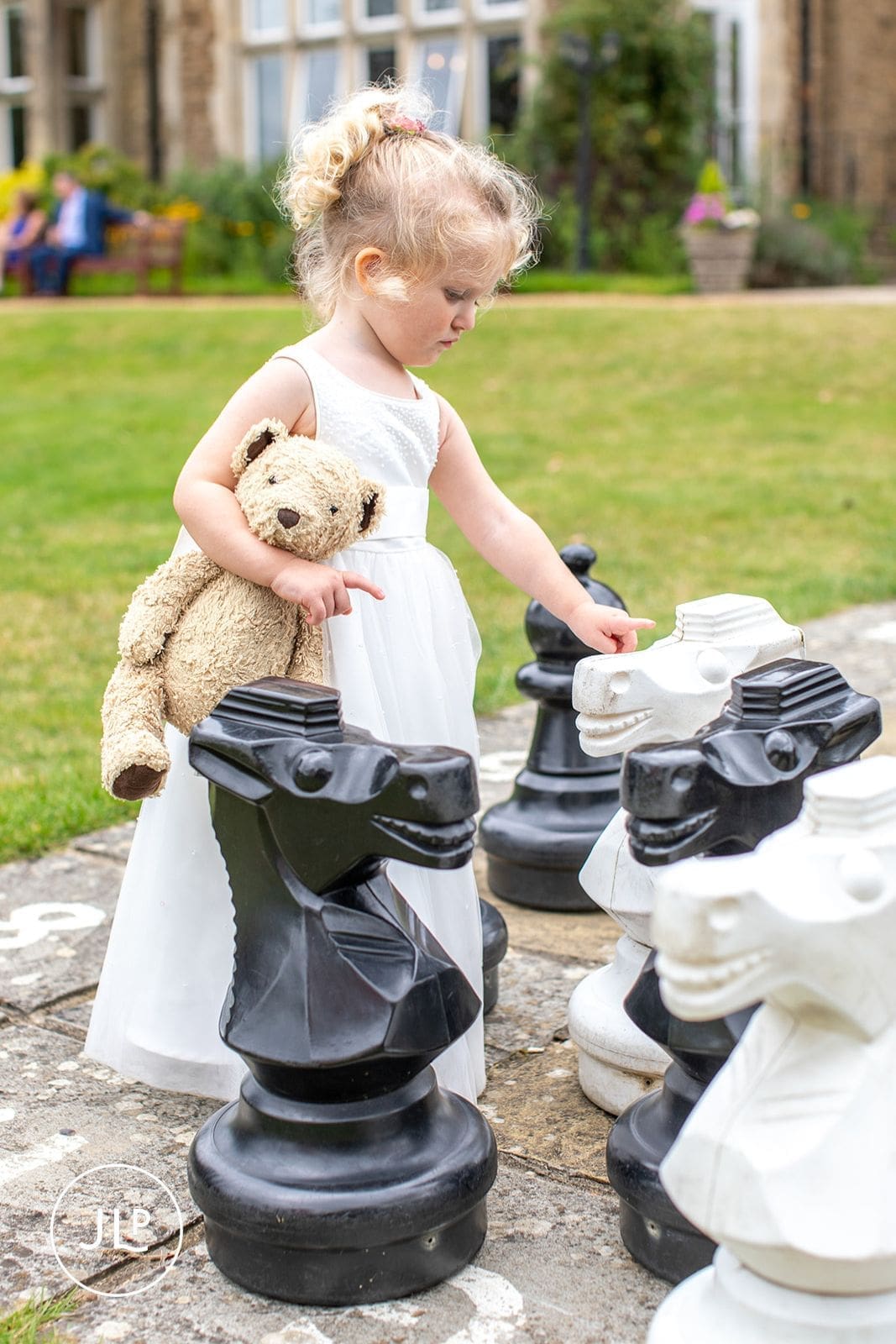 A young wedding guest playing with a giant outdoor chess set during a relaxed marriage celebration.