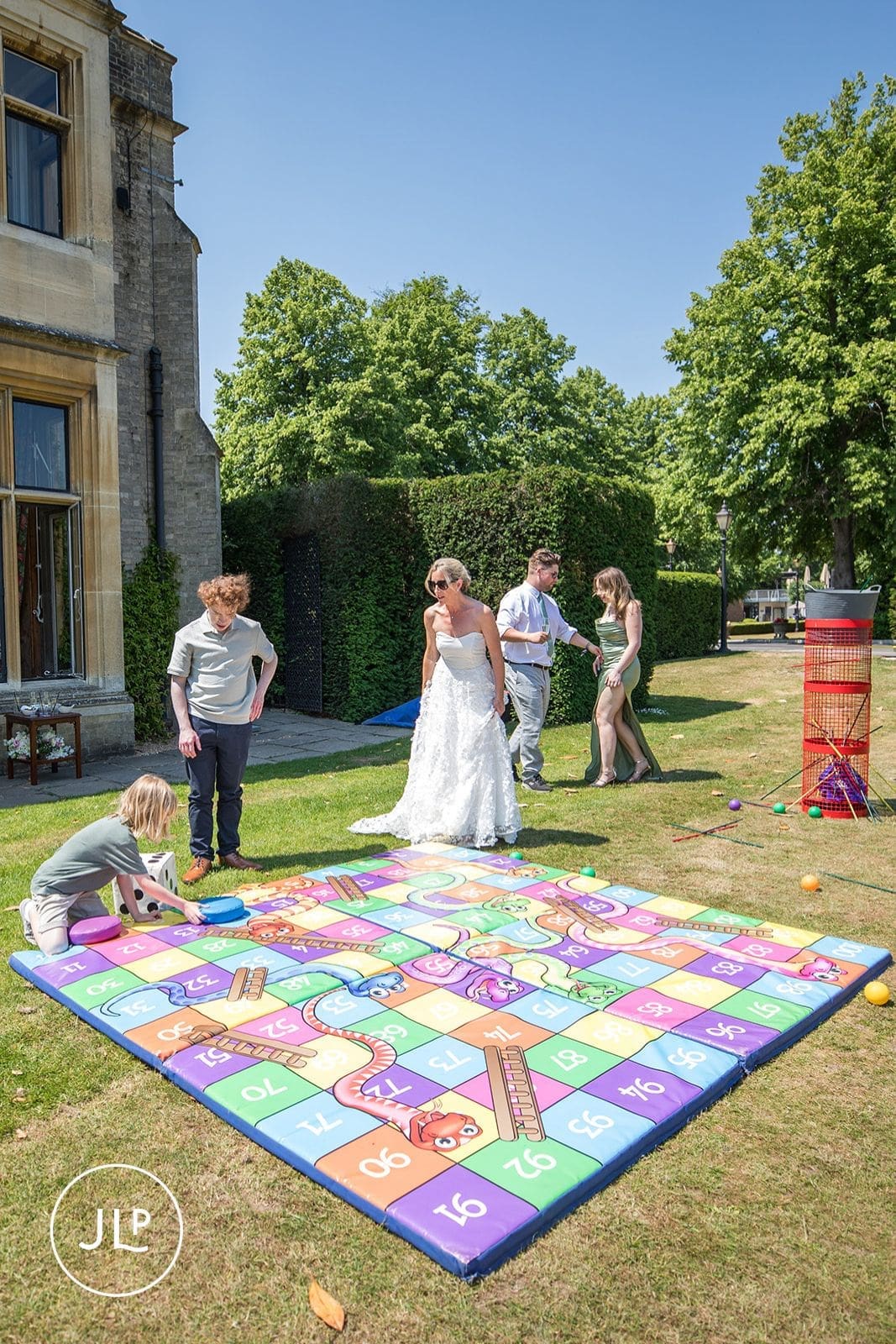 Newlyweds and guests enjoying a giant outdoor board game, a fun idea to keep wedding guests entertained.